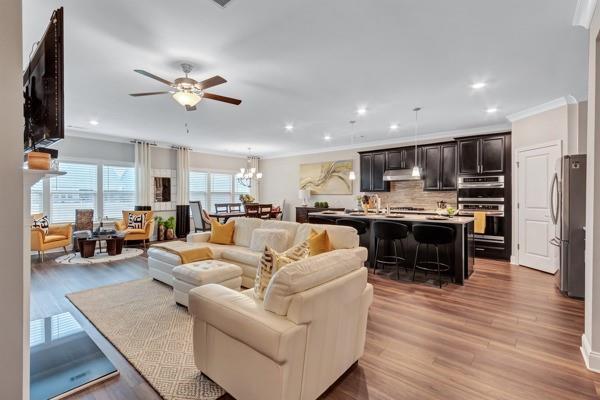 living room with crown molding, ceiling fan with notable chandelier, and light hardwood / wood-style floors