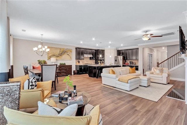 living room featuring ceiling fan with notable chandelier, ornamental molding, and light wood-type flooring