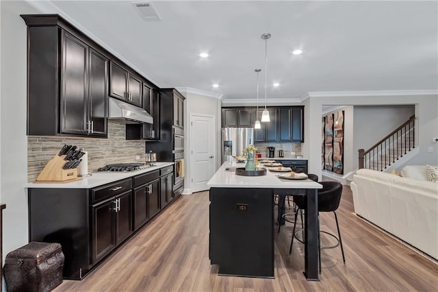 kitchen with a breakfast bar, crown molding, decorative light fixtures, a kitchen island, and stainless steel appliances