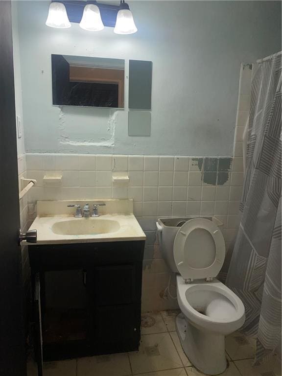 bathroom featuring tile patterned floors, walk in shower, vanity, tile walls, and toilet