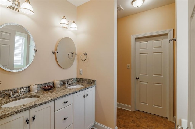 bathroom with double vanity, baseboards, visible vents, and a sink