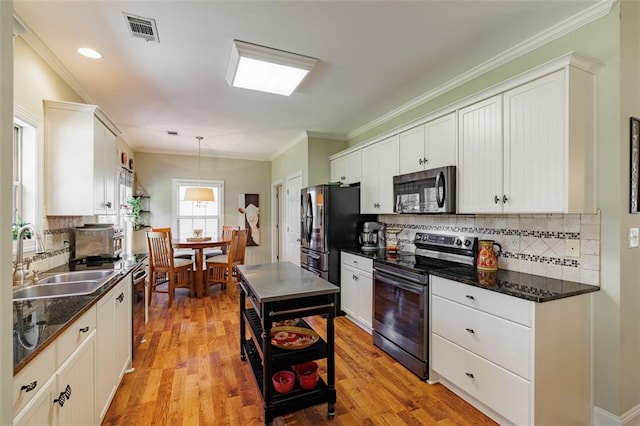 kitchen with light wood finished floors, visible vents, appliances with stainless steel finishes, white cabinetry, and a sink