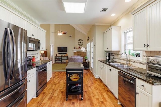 kitchen with visible vents, a sink, stainless steel appliances, vaulted ceiling, and tasteful backsplash