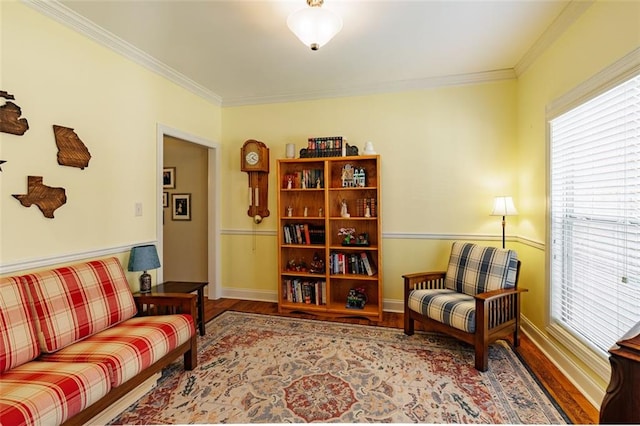 sitting room featuring baseboards, wood finished floors, and crown molding