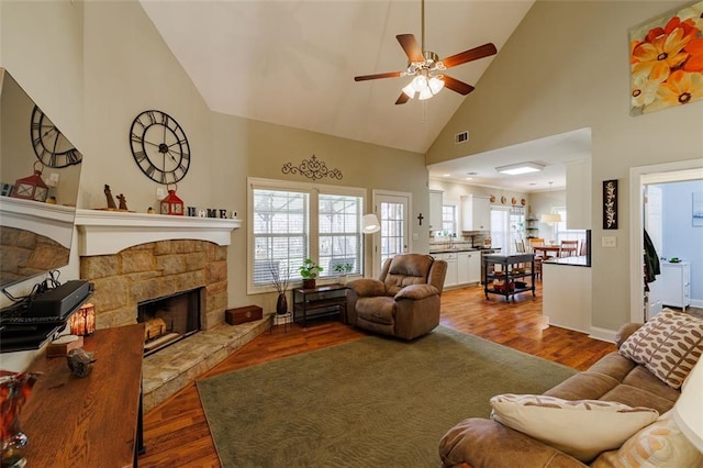 living room with high vaulted ceiling, a ceiling fan, wood finished floors, a fireplace, and baseboards