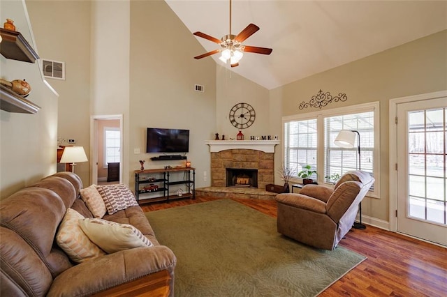 living area featuring visible vents, a healthy amount of sunlight, a fireplace, and wood finished floors