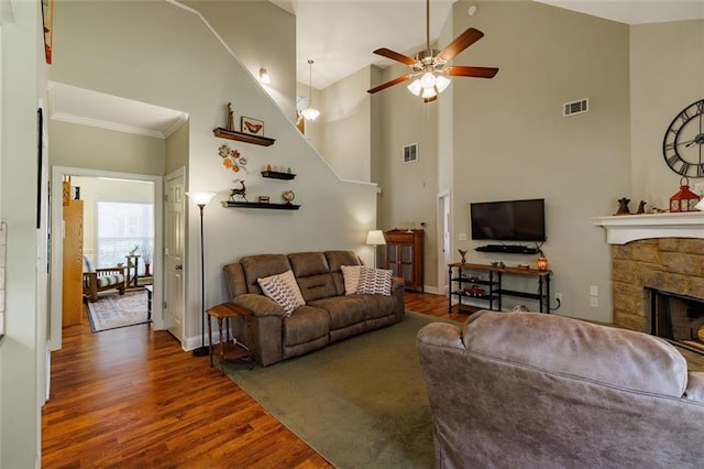 living area featuring visible vents, a high ceiling, wood finished floors, and a fireplace