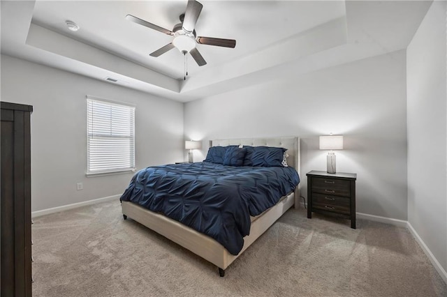 carpeted bedroom with visible vents, baseboards, a raised ceiling, and a ceiling fan