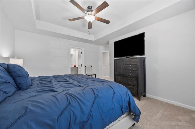 carpeted bedroom with ceiling fan, ensuite bath, a raised ceiling, and baseboards