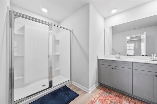 full bath with visible vents, a sink, a shower stall, and wood finished floors