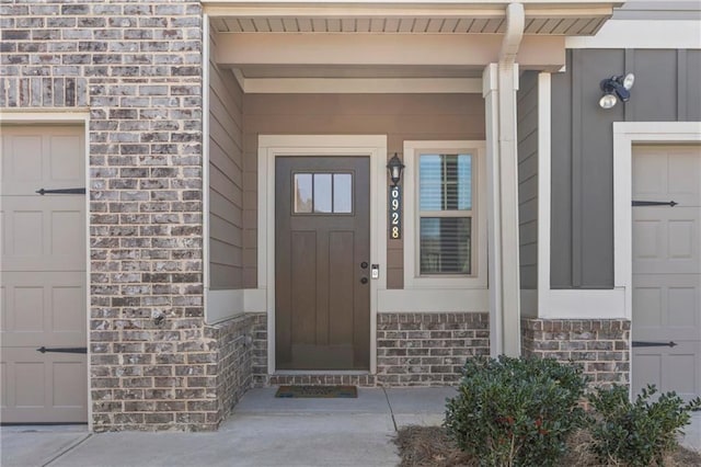 view of exterior entry with a garage, brick siding, and covered porch