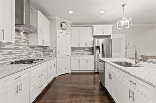 kitchen with a sink, crown molding, wall chimney exhaust hood, stainless steel appliances, and white cabinets