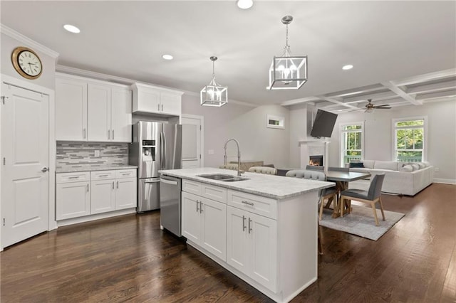 kitchen with a sink, stainless steel appliances, a lit fireplace, and recessed lighting