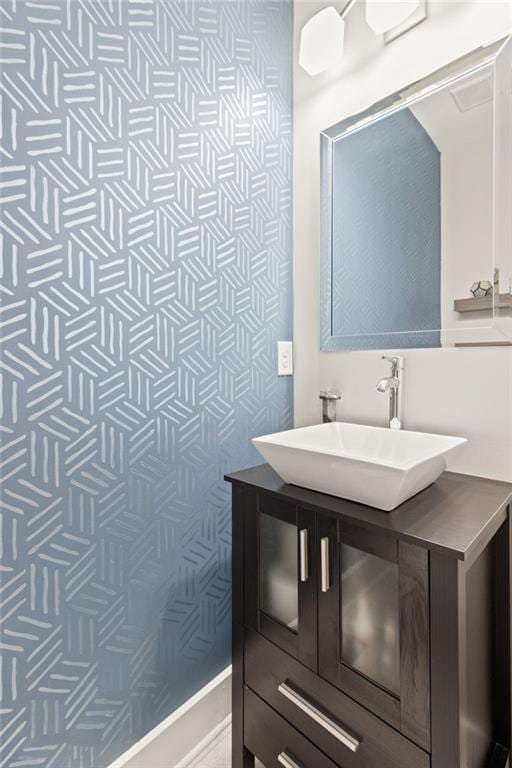 bathroom featuring vanity and wallpapered walls