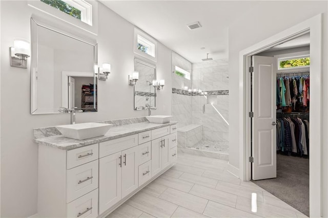full bath with a sink, a healthy amount of sunlight, tiled shower, and visible vents