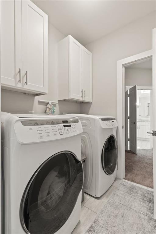 laundry area with separate washer and dryer and cabinet space