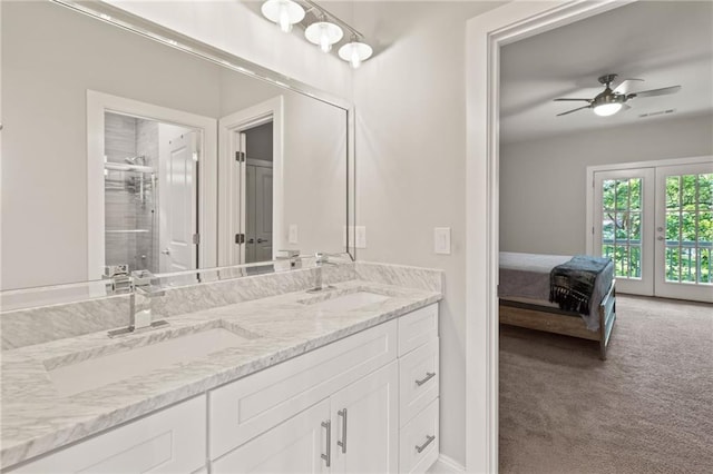 ensuite bathroom with a ceiling fan, double vanity, a sink, and a shower stall