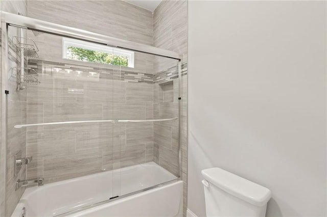 bathroom with combined bath / shower with glass door and toilet