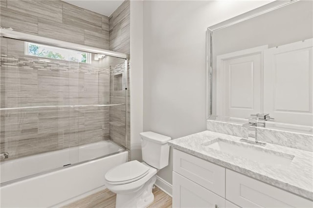 full bath featuring toilet, vanity, wood finished floors, and bath / shower combo with glass door