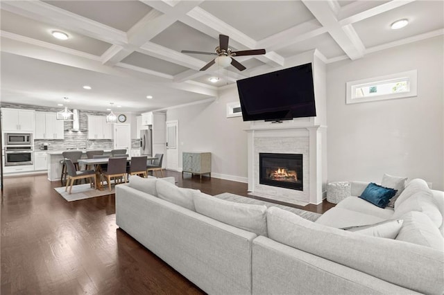 living area featuring coffered ceiling, ceiling fan, beamed ceiling, a stone fireplace, and recessed lighting