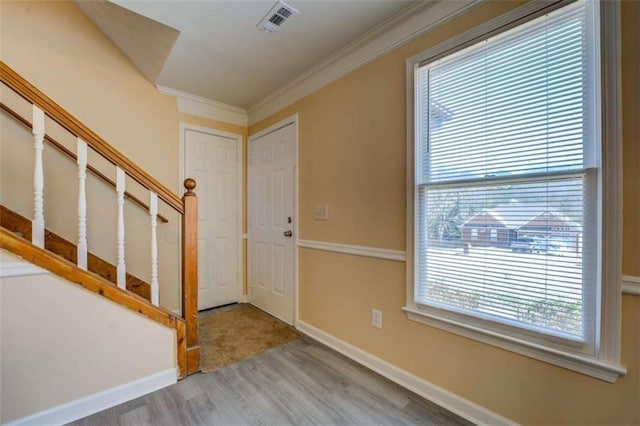 foyer with crown molding, visible vents, stairway, wood finished floors, and baseboards