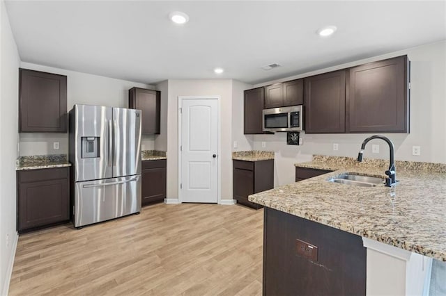 kitchen with light wood-type flooring, stainless steel appliances, dark brown cabinetry, and sink