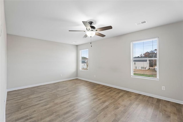 empty room with wood-type flooring, a wealth of natural light, and ceiling fan