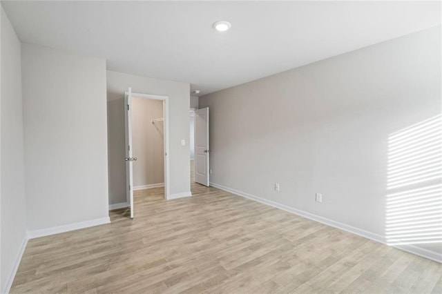 unfurnished bedroom featuring light hardwood / wood-style floors, a walk in closet, and a closet