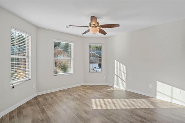 empty room with ceiling fan, plenty of natural light, and light wood-type flooring