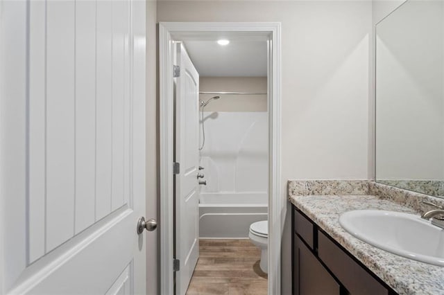 full bathroom with hardwood / wood-style floors, vanity, toilet, and shower / washtub combination