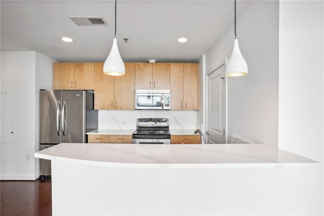 kitchen with appliances with stainless steel finishes, dark hardwood / wood-style floors, pendant lighting, and kitchen peninsula