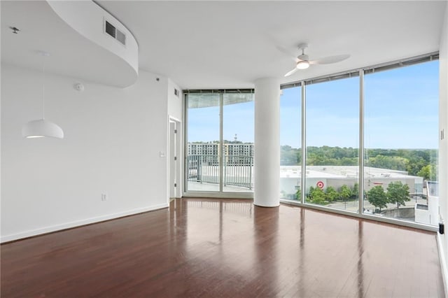 spare room featuring ceiling fan, plenty of natural light, hardwood / wood-style floors, and a wall of windows