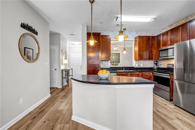 kitchen with stainless steel appliances, hanging light fixtures, backsplash, and light wood-type flooring