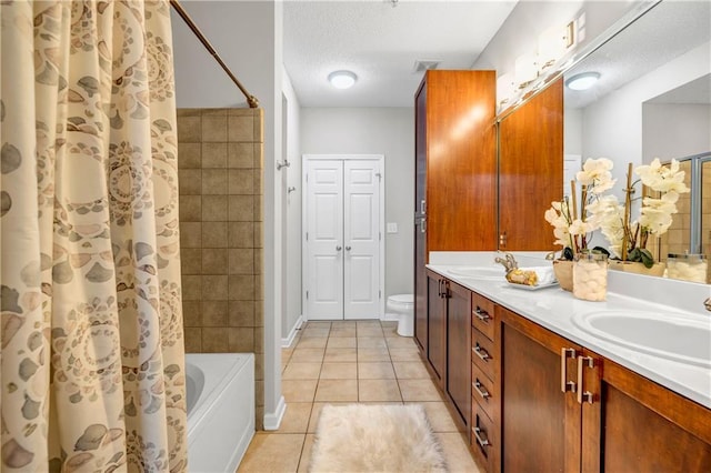 bathroom with tile patterned flooring, vanity, a textured ceiling, and toilet