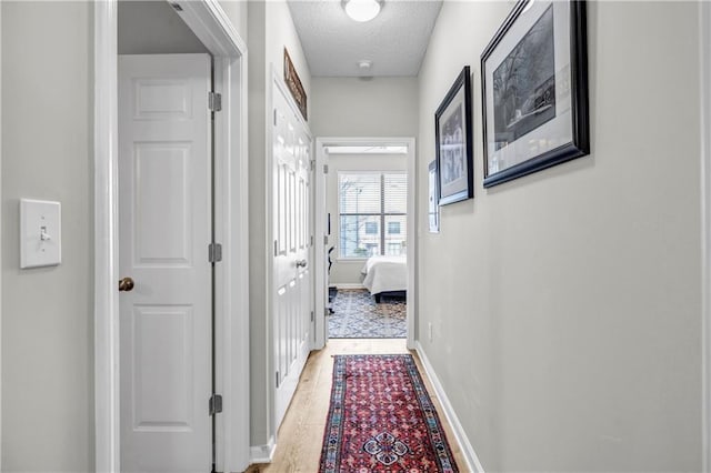 hallway featuring a textured ceiling and light wood-type flooring