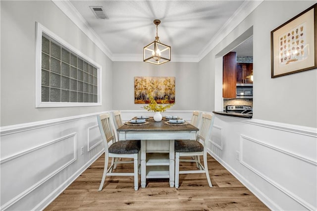 dining space with ornamental molding, a notable chandelier, and light hardwood / wood-style floors