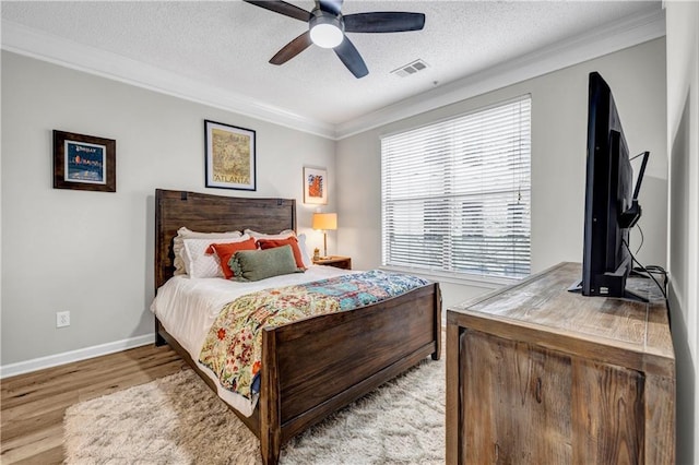 bedroom featuring ceiling fan, ornamental molding, light hardwood / wood-style flooring, and a textured ceiling