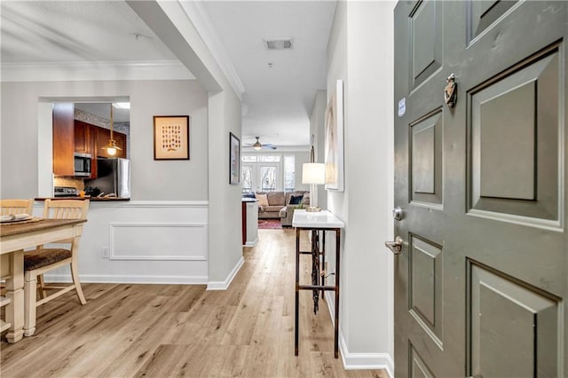 hallway with light hardwood / wood-style flooring and ornamental molding