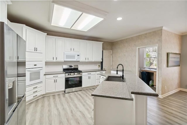 kitchen featuring light wood-style flooring, a sink, appliances with stainless steel finishes, white cabinetry, and crown molding