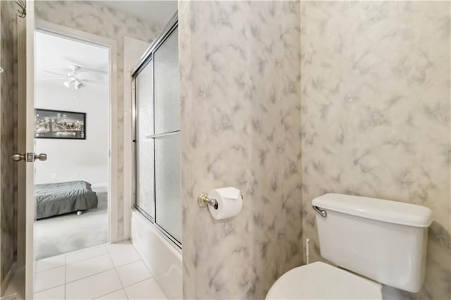 ensuite bathroom with toilet, ensuite bath, combined bath / shower with glass door, tile patterned flooring, and ceiling fan