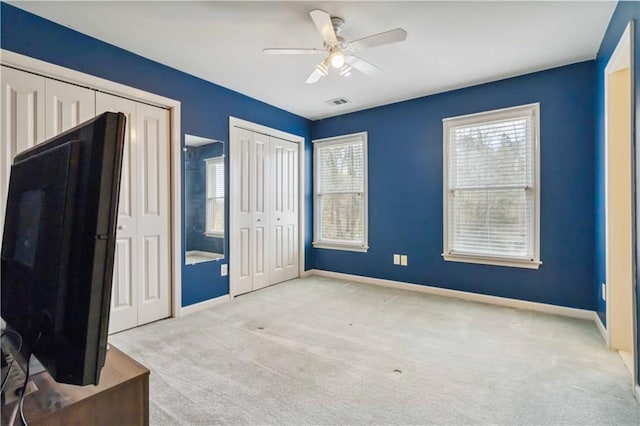 unfurnished bedroom featuring multiple windows, baseboards, two closets, and carpet floors