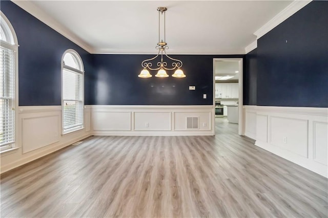 unfurnished dining area with visible vents, a wainscoted wall, a notable chandelier, and wood finished floors