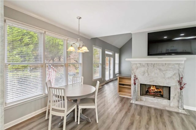 dining room featuring a fireplace, an inviting chandelier, wood finished floors, and baseboards