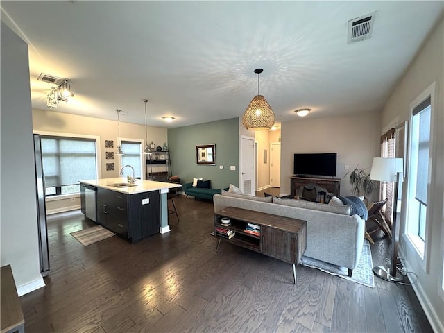 living room with plenty of natural light, dark wood-type flooring, visible vents, and baseboards