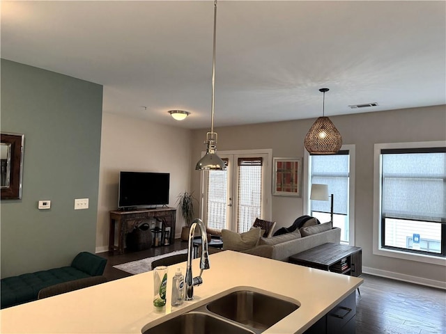 kitchen with open floor plan, pendant lighting, light countertops, and a sink