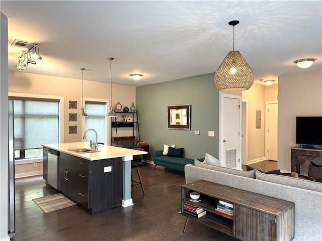 kitchen with visible vents, dishwasher, a sink, open floor plan, and a breakfast bar area