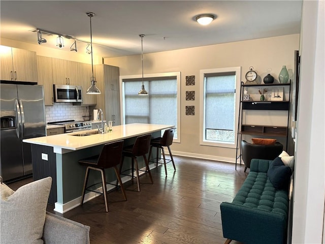 kitchen featuring open floor plan, light countertops, a kitchen bar, stainless steel appliances, and a sink