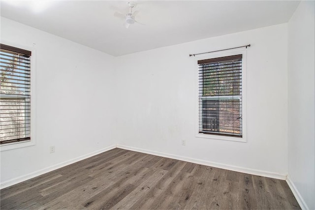 empty room with a wealth of natural light and dark hardwood / wood-style flooring