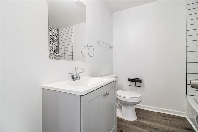 bathroom featuring vanity, hardwood / wood-style floors, a washtub, and toilet