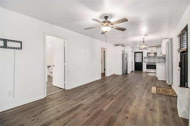 unfurnished living room with ceiling fan with notable chandelier and dark hardwood / wood-style flooring